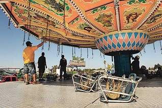 Helms & Sons workers assemble the Wave Swinger on Sunday at the Tulare County Fairgrounds. The ride is one of three on the midway that used to be at Michael Jackson's Neverland. The German-made ride features hand-painted pictures.